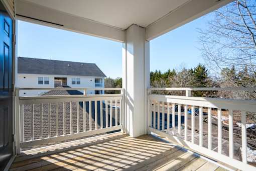 A white deck with a blue door and a white house in the background.