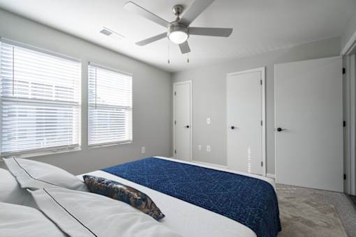 A bedroom with a bed, pillows, and a ceiling fan.