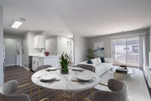 A modern dining room with a round marble table and grey chairs.