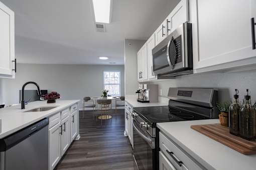 A modern kitchen with white cabinets and black appliances.