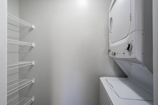 A white dryer is on the right side of a white laundry room.