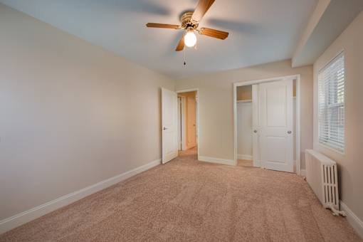 A room with a ceiling fan and carpeted floor.