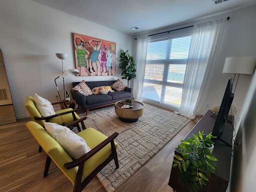 A living room with a couch, chairs, and a painting on the wall.