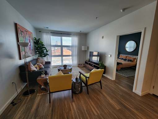 A living room with a yellow chair and a couch.