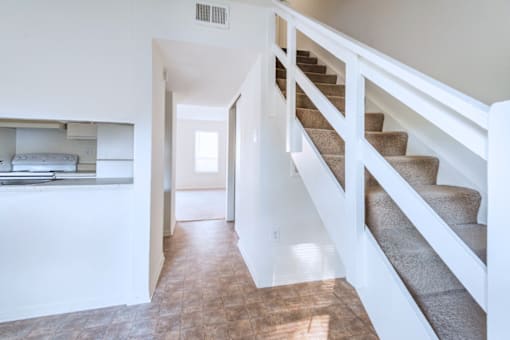 A staircase with a white railing and beige carpeted steps.