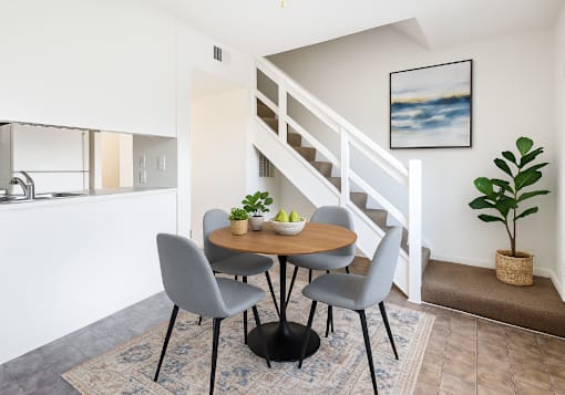 A dining area with a round table and grey chairs.