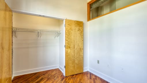 an empty room with white walls and a wooden floor and a mirror on the wall