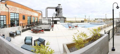 the pool and patio area of a building with chairs and tables
