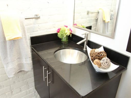 a black bathroom counter with a sink and a mirror