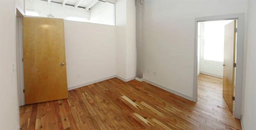 an empty room with a wooden floor and a door