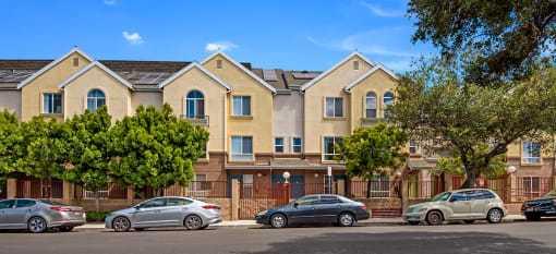 a row of apartment buildings with cars parked in front of them