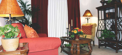 a living room with a red couch and a table with flowers at Senior Living at Henson Village