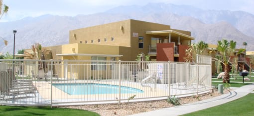 Vista Sunrise Apartments clubhouse with a pool behind a fence