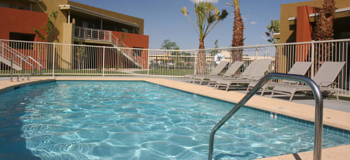 a swimming pool at Vista Sunrise Apartments with chairs and a fence