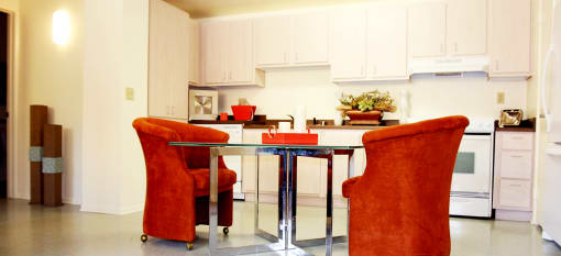 a kitchen and dining room with orange chairs and a table at Vista Sunrise Apartments
