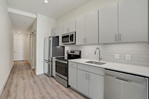 a white kitchen with stainless steel appliances and white cabinets at Sinclaire on Seminary, Alexandria, 22311