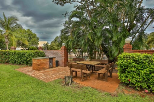 A patio with a table and chairs surrounded by greenery.