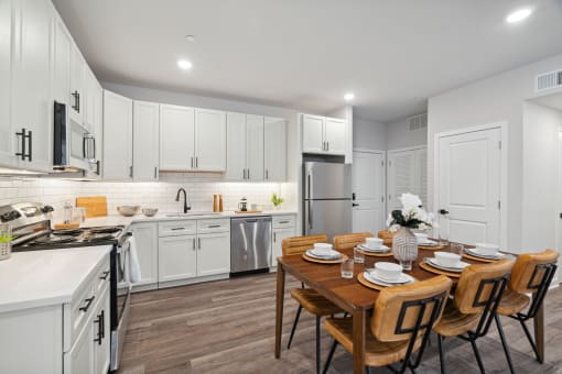 a kitchen with white cabinetry and a wooden dining table