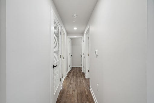 a hallway with white walls and wooden floors