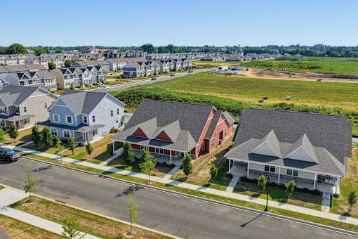 A suburban street with houses on both sides and a car parked on the side of the road.