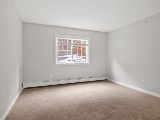 Empty bedroom with a window and carpet  at the River, Manchester, 03102
