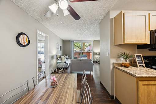 A kitchen with a table and chairs in the foreground and a dining area in the background.