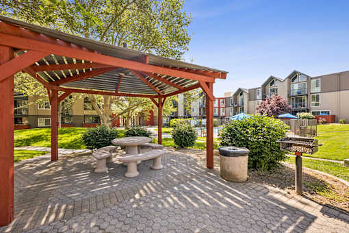 A patio with a table and benches under a pergola.