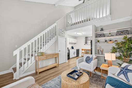 A living room with a staircase and a dining area.at Lofts of Wilmington, North Carolina, 28405