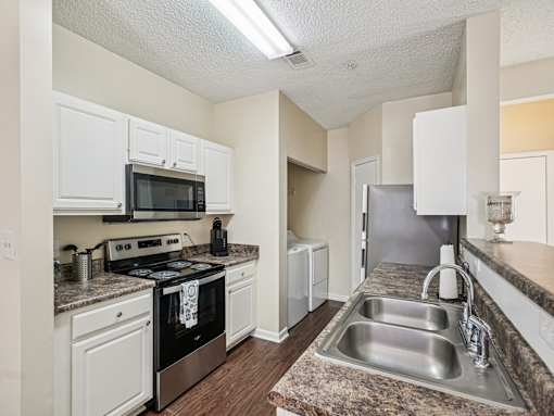 A kitchen with a black oven and white cabinets. at Cedar Springs Apartments, North Carolina, 27609