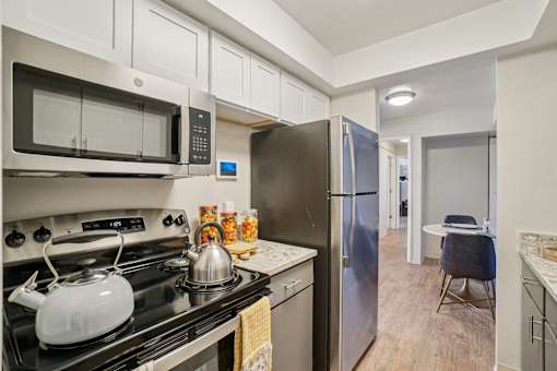 A kitchen with a black stove top and a silver refrigerator.