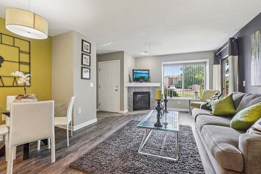 A modern living room with a glass coffee table and a grey sofa.