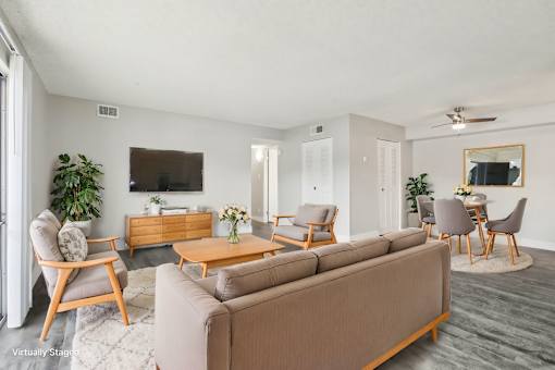 A living room with a brown sofa, wooden chairs, and a TV on the wall. at Spyglass Creek, Denver, 80224