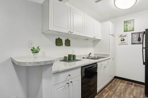 A kitchen with white cabinets and a black refrigerator. at Millennium at Creve Coeur, Missouri