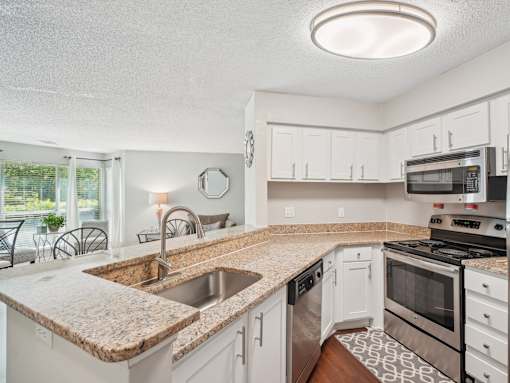 A kitchen with a granite countertop and stainless steel appliances. at University Ridge Apartments, North Carolina, 27707