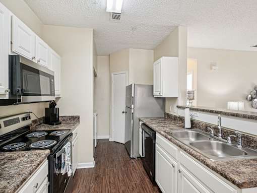 A kitchen with a stove, microwave, refrigerator, and sink. at Cedar Springs Apartments, North Carolina