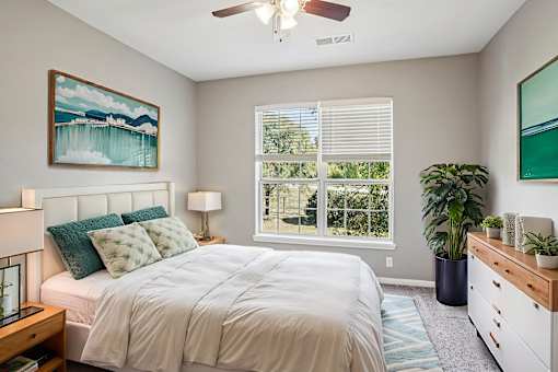 A bedroom with a bed, a ceiling fan, and a painting on the wall. at Bridford Lake Apartments, North Carolina, 27407