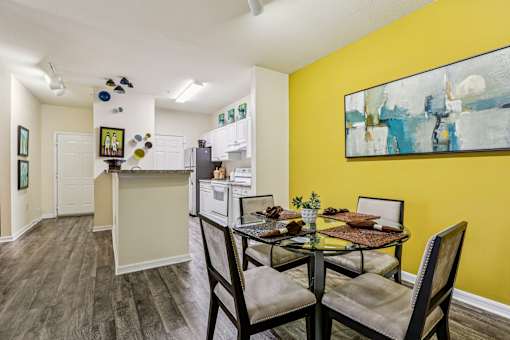 Dining area with glass table and modern kitchen at The Arbor Walk Apartments, Tampa, FL