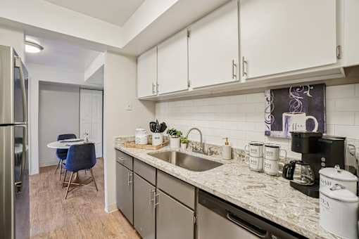 A kitchen with a sink, a refrigerator, and a dining table.