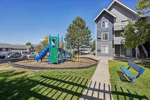 A playground with a blue slide and a green slide in the foreground with a building in the background. at Windmill Apartments, Colorado, 80916