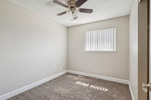 A room with a ceiling fan and a window with blinds.at Aspen Townhomes, Colorado Springs, CO