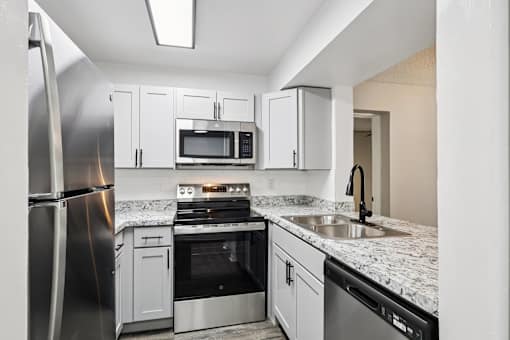 A kitchen with a refrigerator, microwave, oven, and sink. at Lakeside Glen Apartments, Melbourne, FL
