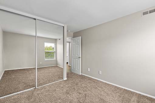 Bedroom with a mirrored closet and carpeted floors at Creve Coeur, Creve Coeur, MO