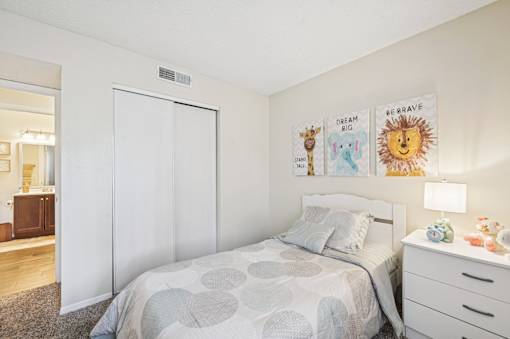 A bedroom with a bed, nightstand, and a wall hanging with the words  at Sarasota South Apartments, Florida