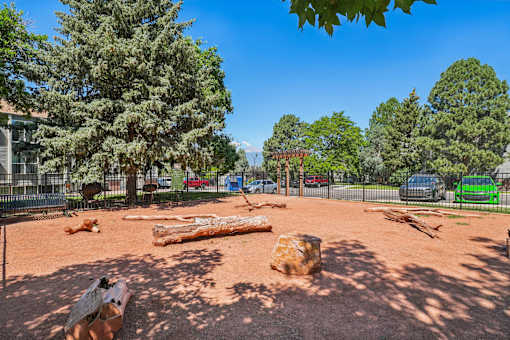 A playground with a large log and a tree in the background.