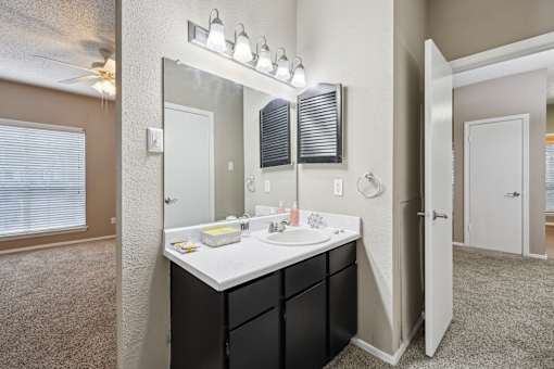 A bathroom with a sink, mirror, and lighting fixture.