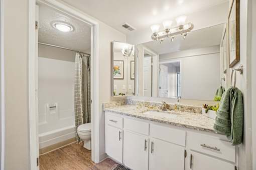 A bathroom with a marble countertop and white cabinets.