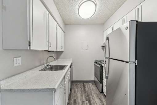 A kitchen with a black refrigerator and white cabinets at Spyglass Creek, Denver, 80224