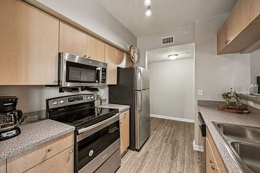 A kitchen with a stove, microwave, and refrigerator. at Heritage Bay, Jensen Beach, FL