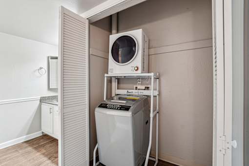 A washing machine is in a small room with a door open. at Glen at Lakewood, Colorado, 80228