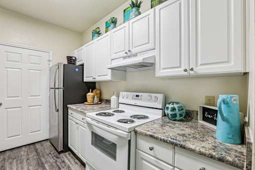 White kitchen with electric stove and granite counters at The Arbor Walk Apartments, Tampa